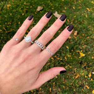 Close-up of S925 sterling silver rings with diamonds and pearls on a hand outdoors
