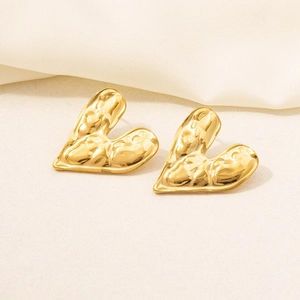 Macro detail of gold 18K plated heart earrings with hammered metal texture on stone