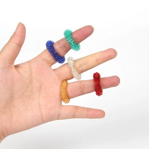 Close-up of five colorful spring finger massage rings in green, blue, silver, gold, and red
