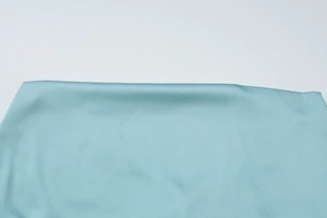 Detailaufnahme von petrolfarbenem Satinstoff mit seidigem Fall und elegantem Glanz