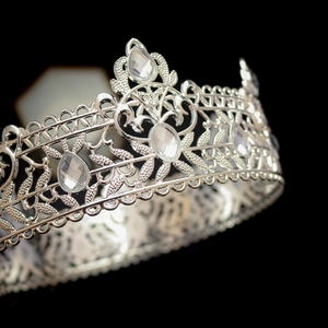 Detailed close-up of vintage baroque silver crown with intricate filigree and sparkling gems