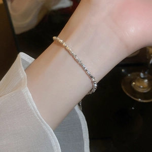 Detail of minimalist faceted silver bead bracelet on wrist with elegant white shirt sleeve