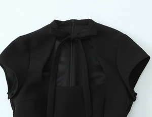 Detail of high neck polka dot dress featuring a bow tie and front square cutout