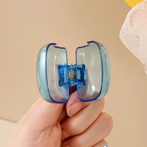 Blauer transparenter Acryl-Haarclip mit starker Metallfeder in der Hand gehalten