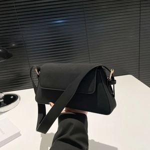 Detail of black vintage baguette bag in matte finish with gold hardware held by hand
