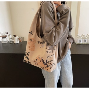 Detail of beige canvas tote bag featuring cute cartoon animal illustrations and cursive text