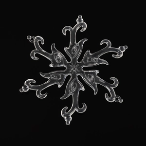 Macro detail of transparent crystal snowflake ornament with intricate curls on black background