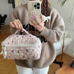 Detail of pink quilted bear makeup bag featuring a convenient top handle and zipper