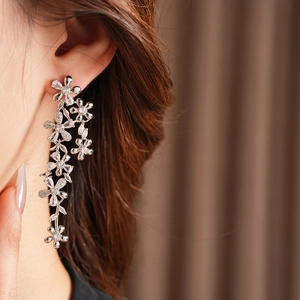 Close-up of sparkling flower tassel earrings with zircons on a model for a luxury look