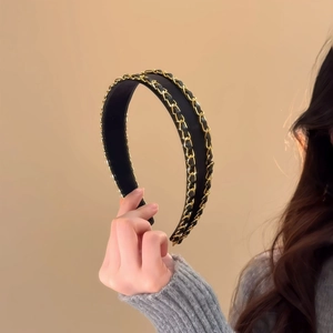 Close-up of black fabric headband with double gold chain and interwoven leather detail