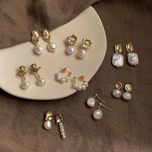 Flat lay of vintage baroque pearl earrings set in gold finish on rustic linen cloth