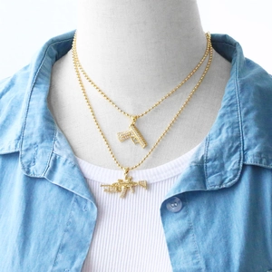 Detail of hip hop gold plated machine gun pendants with iced out rhinestones on ball chain