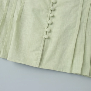Detail of mint green cotton fabric featuring fabric-covered buttons and pleated texture