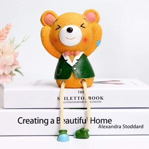 Detail of yellow resin bear figurine in green suit sitting on decorative books
