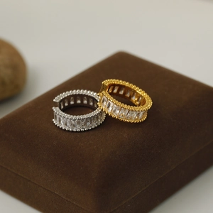 Macro detail of gold and silver huggie earrings with rectangle crystals on velvet