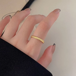 Detail of 925 sterling silver ring with gold finish and wheat braid texture on finger