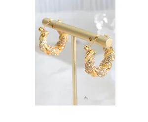 Macro view of gold-plated twisted U-shaped earrings with micro-pave cubic zirconia crystals