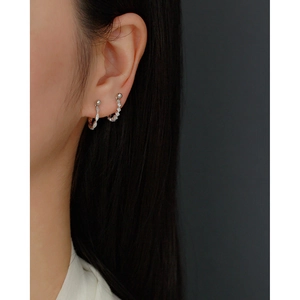 Macro shot of silver S925 geometric earrings with pavé crystals on a model ear