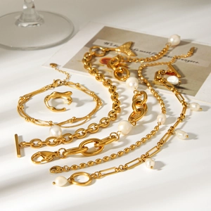 Flat lay of gold layered pearl bracelet and chain necklace jewelry set on white background