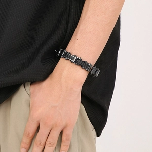 Close-up of men's black stainless steel bicycle chain bracelet worn on a wrist