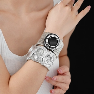 Close-up of woven silver wire bracelet with a central black stone and spiral wire detail