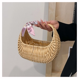 Detail of woven straw basket bag with pink floral scarf wrapped around the handle