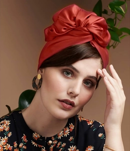 Detailaufnahme eines roten Satinturbans mit stilvollem Knoten und Retro-Schleifen-Design