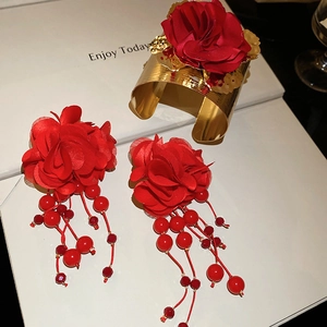 Detail of red fabric rose jewelry set with gold textured arm cuff and beaded earrings