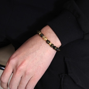 Buddhist black onyx bracelet with golden Buddha head and mantra beads on man wrist