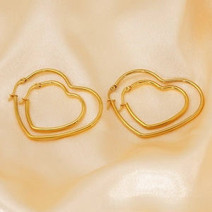 Vue macro de deux paires de créoles cœur polies plaquées or 18 carats sur tissu satin