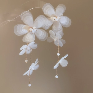Detailed close-up of white chiffon flower earrings with golden chains and small pearls