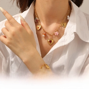 Close-up of gold chain necklace and bracelet set with ceramic heart and mushroom charms