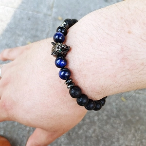 Close-up of beaded wolf head bracelet with natural tiger eye and lava stones on wrist