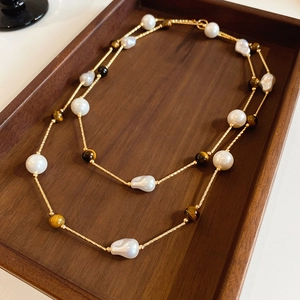 Detailed shot of double-layer gold chain necklace with baroque pearls and tiger eye stone