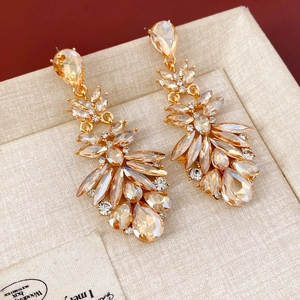 Gros plan de boucles d'oreilles pampilles en cristal champagne sur boîte en lin