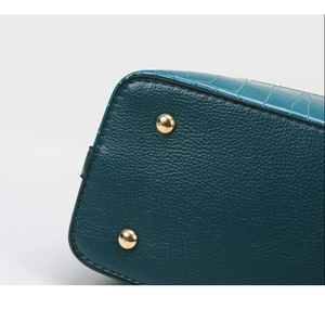 Detail of embossed leather bucket bag bottom with golden studs and crocodile texture
