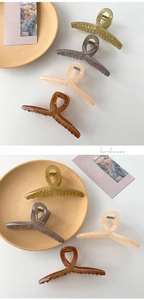 Detail of large matte claw clips in olive, amber, and grey on a ceramic tray