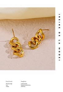 Macro shot of gold-plated stainless steel interlocking Cuban chain earrings on textured stone