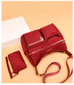 Deep red waterproof nylon shoulder bag with multiple zippered pockets and small pouch