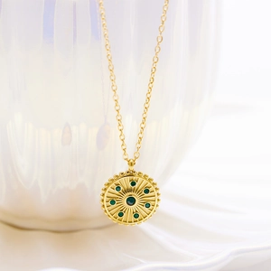 Vue détaillée du pendentif vintage doré avec des pierres précieuses en zircon vert