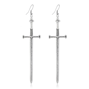 Gros plan de boucles d'oreilles pendantes en forme d'épée argentée avec texture métal