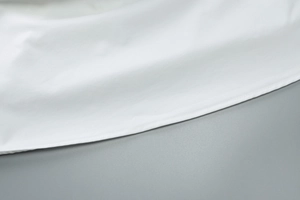 Détail de la couture précise et texture douce sur l'ourlet de la robe blanche