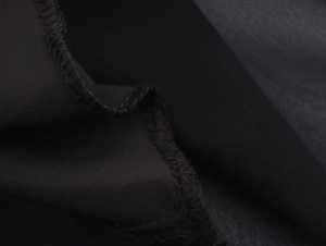 Dettaglio macro del pizzo nero e cuciture professionali overlock sul vestito elegante