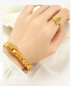 Detail of gold-plated watchband bracelet and heart-shaped ring with textured design