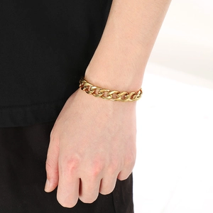 Close-up of a chunky gold-plated stainless steel curb chain bracelet worn on a wrist