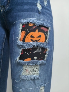 Makroansicht von blauen Jeans mit festlichen Halloween-Kürbis- und Totenkopf-Patches