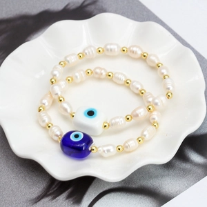 Freshwater pearl bracelets with blue and white evil eye pendants in a white ceramic dish