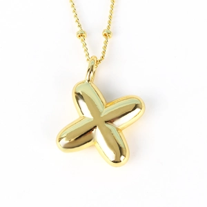 Macro shot of polished gold-finished X-shaped pendant necklace with reflective metal surface