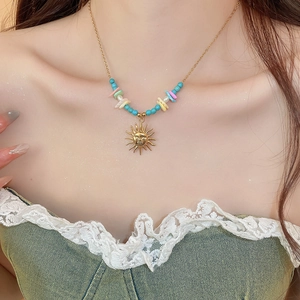 Detail of bohemian sun pendant necklace with colorful beads on a model collarbone