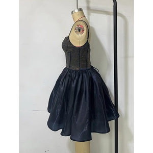 Detail of navy blue prom dress featuring gold stud bodice and satin pleated skirt